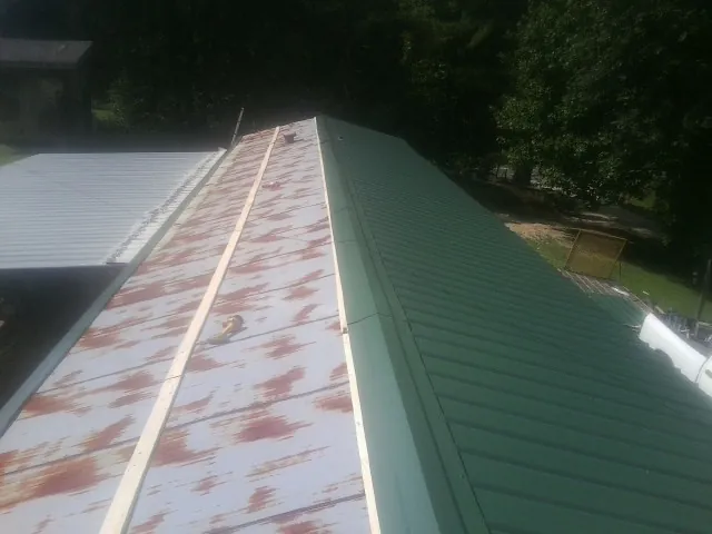 Old rusted panels beside newly installed green metal roofing — Wind Damage Roof Repair by Roofing Brothers in Ruffin