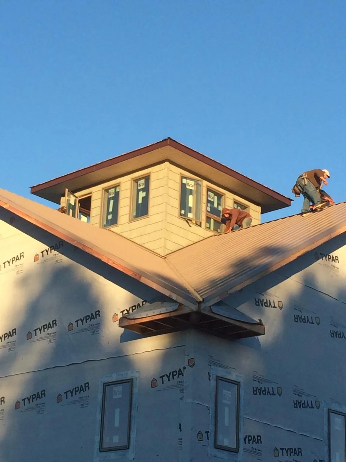 Roofers working around a rooftop cupola on a new metal roof at sunset — Roof Waterproofing in Ruffin by Roofing Brothers